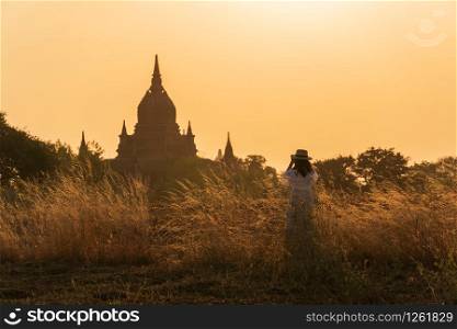 Amazing signseeing in Bagan. Woman take a photo of pagoda and waiting for sunset.