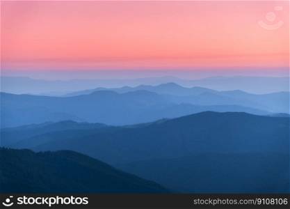 Amazing silhouettes of a mountains at colorful sunset in summer in Ukraine. Landscape with mountain ridges in fog, pink sky in the evening. Nature background. Hills at twilight. Scenery 