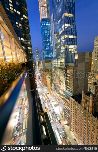 Amazing skyscrapers in Midtown Manhattan, aerial view from rooftop with traffic reflections on the buildings at night.