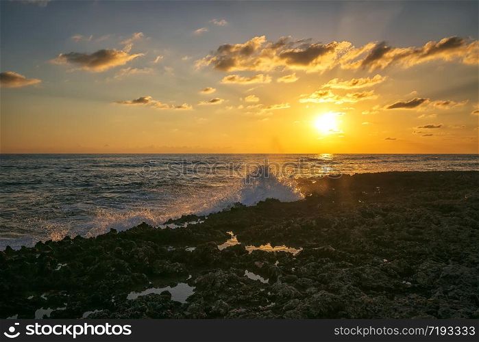 Amazing splash of seawater at sunset on coral rocks. Caribbean Cuba