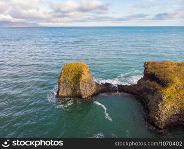 Amazing stone arch Gatklettur basalt rock on Atlantic coast of Arnarstapi in Iceland. The famous natural form arch attracts tourist to visit west of Iceland.