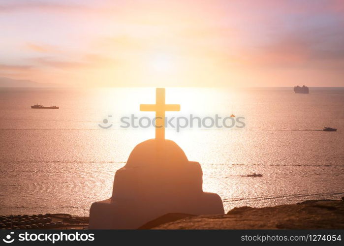 Amazing sunset colors of Aegean sea. Orthodox church cross, christianity religion symbol. Mykonos island. Greece
