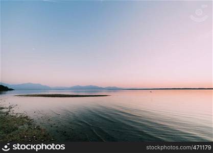 Amazing sunset in chiemsee lake with pink and blue colors and the mountains in background
