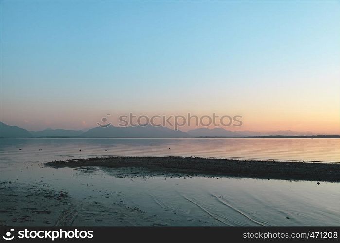 Amazing sunset in chiemsee lake with pink and blue colors and the mountains in background