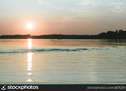 Amazing sunset in chiemsee lake with sailboat navigating