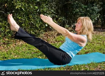 Amazingly fit and beautiful mature woman doing an advanced pilates move.