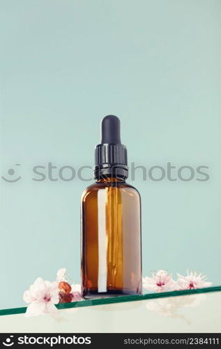 Amber glass dropper bottle with black lid on glass transparent shelf, green background. SPA natural organic beauty product packaging design, branding. Beauty salon mockup, low angle view, below the eye line, looking up, hero view. Amber glass dropper bottle and cherry blossom flower on glass transparent shelf, green background. Skincare products , natural cosmetic. Beauty concept for face and body care, ow angle view,