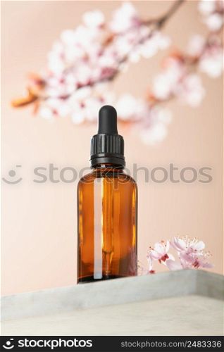 Amber glass dropper bottle with black lid on white marble shelf, natural spring  background. SPA natural organic beauty product packaging design, branding. Beauty salon mockup, low angle view, below the eye line, looking up, hero view
