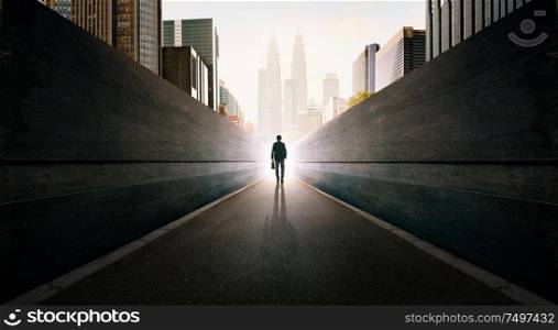 Ambitions concept with businessman walking from alley to modern city .