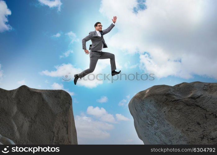 Ambitious businessman jumping over the cliff