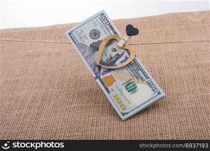 American 100 dollar banknotes with a heart clip on a string