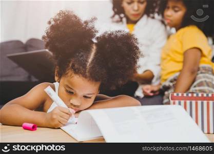 American Black preschool daughter kids doing homework learning education with her sister living together at home.