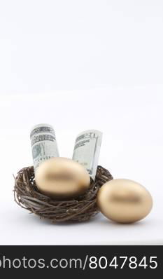 American currency placed with gold nest eggs. Vertical image with copy space above on white background.