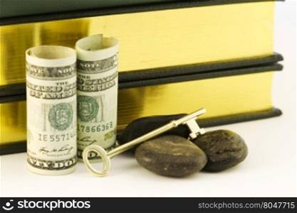American currency with books, key, and rocks symbolizes the strategic investment goal of money for education and its difficult attainment in rocky times.