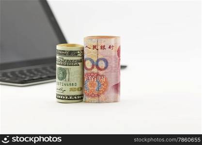 American dollar and Chinese yuan currencies in front of tablet screen and keyboard reflect global trends of investment in technology