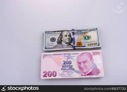 American dollar banknotes and Turksh Lira banknotes side by side on white background