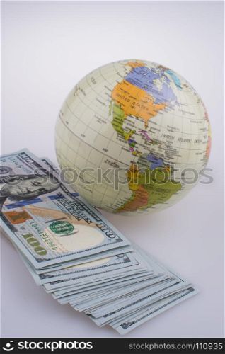 American dollar banknotes by the side of a model globe on white background