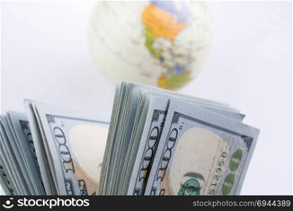 American dollar banknotes by the side of a model globe on white background