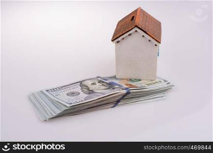 American dollar banknotes on the roof of a model house on white background