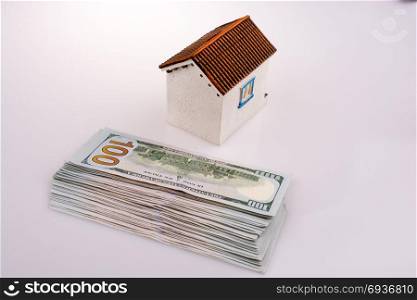 American dollar banknotes on the roof of a model house on white background