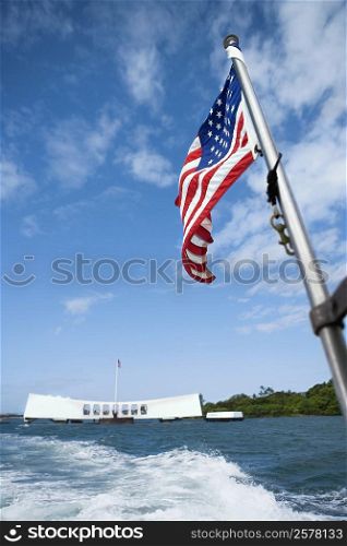 American flag fluttering with a memorial building in the background, Pearl Harbor, Honolulu, Oahu, Hawaii Islands, USA