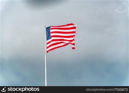 American flag waving against stormy sky.