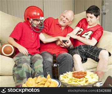 American football fans- father and sons - fighting for the television remote control.