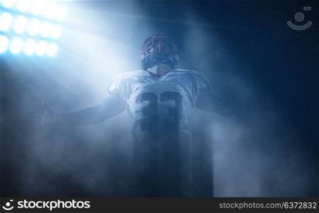 american football player celebrating after scoring a touchdown on field at night