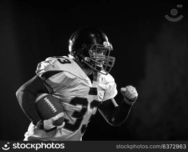 American football player holding ball while running on field at night