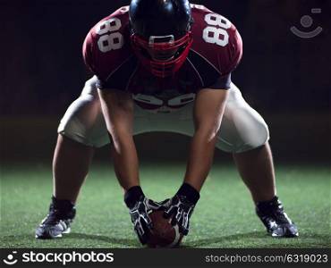 American football player starting football game on american football field at night