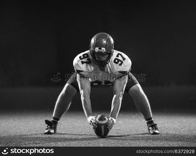 American football player starting football game on american football field at night