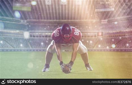 American football player starting football game on big modern american football field with lights and flares at night