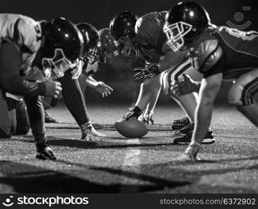 american football players are ready to start on field at night