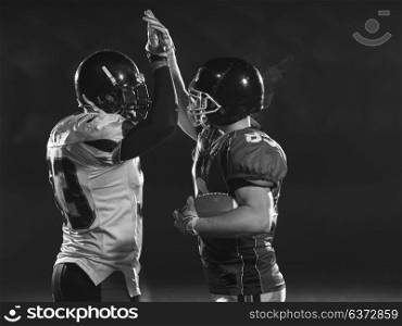 american football players giving high fives after scoring a touchdown on field at night