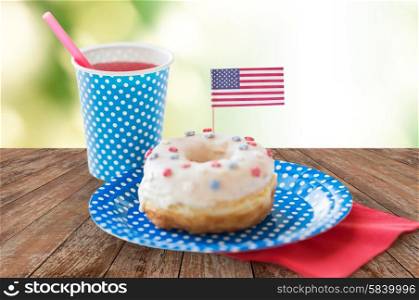 american independence day celebration, patriotism and holidays concept - close up of donut decorated with flag and juice in disposable tableware on wooden table at 4th july party over green background