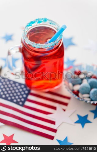 american independence day, celebration, patriotism and holidays concept - close up of juice in glass mason jar mug, flag and stars at 4th july party. mug of juice and american flag on independence day