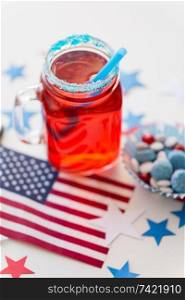 american independence day, celebration, patriotism and holidays concept - close up of juice in glass mason jar mug, flag and stars at 4th july party. mug of juice and american flag on independence day