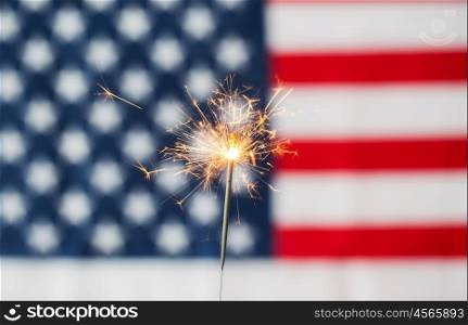 american independence day, patriotism, holidays and celebration concept - close up of sparkler burning over american flag