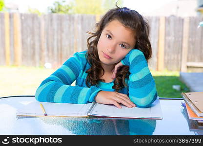 American latin teen girl relaxed on table doing homework on backyard