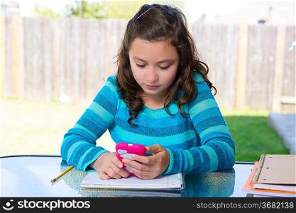 American latin teen girl with smartphone doing homework on backyard