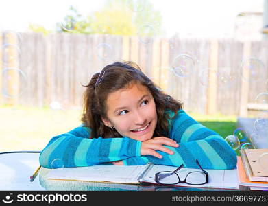 American latin teen girl with soap bubbles doing homework on backyard