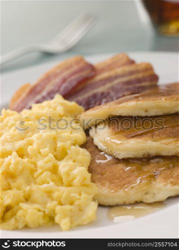 American Pancakes with Crispy Bacon and Scrambled Eggs and Maple Syrup