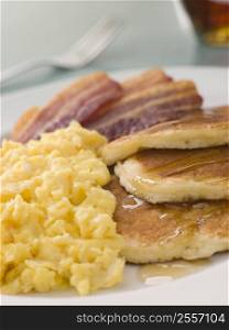 American Pancakes with Crispy Bacon and Scrambled Eggs and Maple Syrup