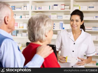 American pharmacist dispensing to senior couple