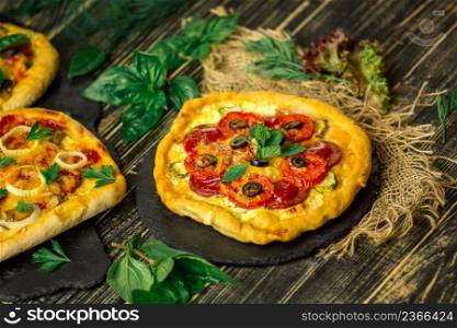 American pizza with mozzarella, tomato, pepperoni on dark wooden table. Sliced pepperoni pizza topping. American pizza on wooden board and various ingredients. American style pizzerias.
