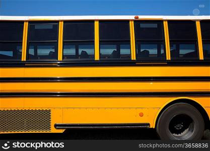 American typical school bus side view on blue sky day