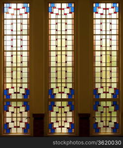 AMERSFOORT, THE NETHERLANDS - SEPTEMBER 3: Three vertical stained glass windows leave a colourful pattern from white, creme, yellow, orange and brown to red and blue in the sunlight on september 3, 2010 in Amersfoort, the Netherlands.