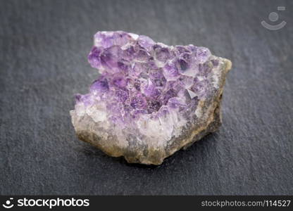 amethyst cluster - a gemstone on gray slate stone background