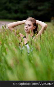 Among the grass. Beautiful young woman among the grass in a field