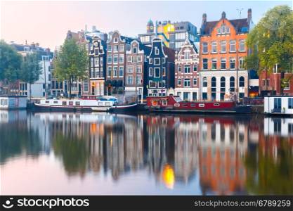 Amsterdam canal Amstel with typical dutch houses and boats during sunrise, Holland, Netherlands.